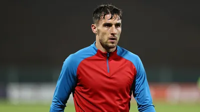Mid-30s athletic male footballer, lean build, waist-up in a tight training session, face sharply focused, eyes intent...