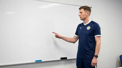 Former Northern Ireland international Niall McGinn, 39, stands in front of a whiteboard, discussing tactics with Derry...